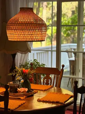 a dining room table with a lamp and flowers on it at Pušyno apartamentai in Druskininkai