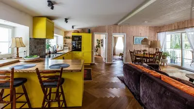a kitchen with yellow cabinets and a couch at Pušyno apartamentai in Druskininkai