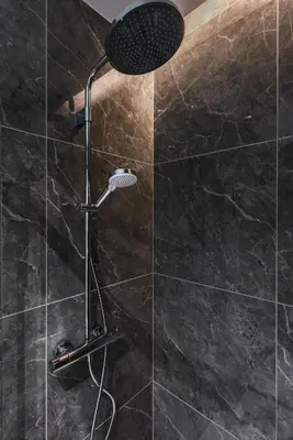a shower with a shower head in a bathroom at cohost I Trendy Apt w- Balcony & Garage Parking in Vilnius