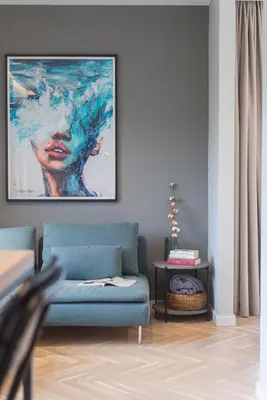 a living room with a blue couch and a painting on the wall at cohost I Trendy Apt w- Balcony & Garage Parking in Vilnius