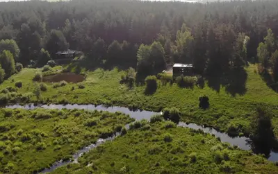 an aerial view of a field with a house and a river at Konga Stay L in Aluona