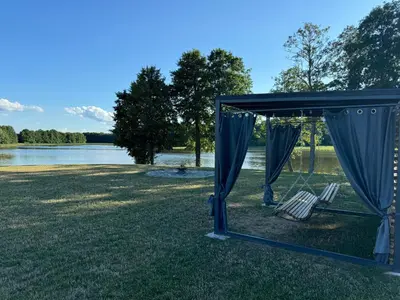 a blue canopy with two chairs and a lake at Panacea in Lazdijai