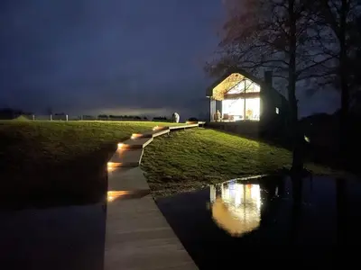 a building with lights on the side of a river at night at Panacea in Lazdijai
