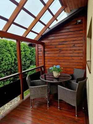 a patio with a table and chairs on a deck at Linos Apartamentai in Druskininkai