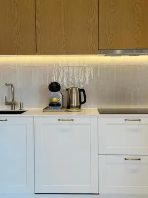 a kitchen with white cabinets and a tea kettle at Poeto Namas Art in Anykščiai