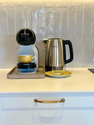 a coffee maker sitting on a counter next to a glass at Poeto Namas Art in Anykščiai