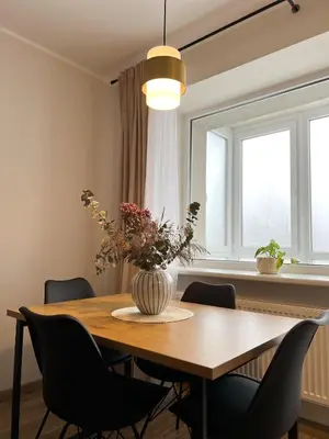 a dining room table with chairs and a vase with flowers at AL Apartment, Central & Cozy in Panevėžys