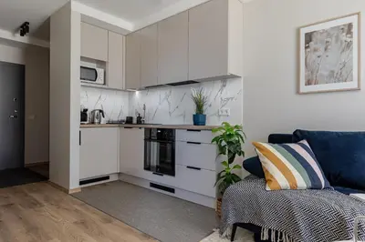 a kitchen with white cabinets and a blue couch at Amber Apartment Free Parking - Self Check In in Vilnius