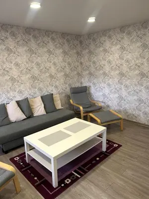 a living room with a couch and a table and chairs at White apartment in Druskininkai