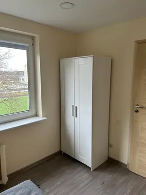 a room with a white cabinet and a window at White apartment in Druskininkai