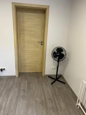a room with a door and a fan next to a floor at White apartment in Druskininkai