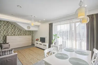a living room with a white table and chairs and a television at Vila Nikolas in Druskininkai