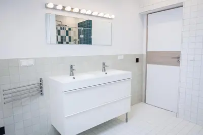 a white bathroom with a sink and a mirror at Vila Nikolas in Druskininkai