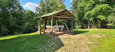 a wooden gazebo with a bench in a field at Sodyba Lakaja Sky in Lakaja