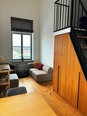 a living room with a couch and a staircase at KaunasInn Loft in Kaunas