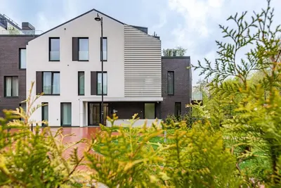 a white house with black windows and trees at Spacious luxury apt w/river view/terrace Paupys in Vilnius