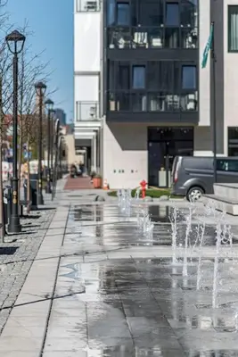 a water fountain on a city street with a building at Spacious luxury apt w/river view/terrace Paupys in Vilnius