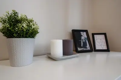 a white table with a plant in a vase and pictures at Cozy Loft / Near Gates of Dawn / Free Netflix in Vilnius