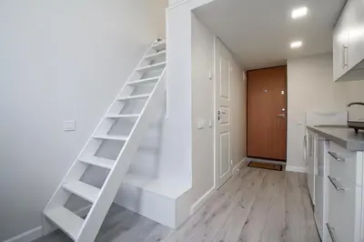 a white staircase in a kitchen next to a room at Cozy Loft / Near Gates of Dawn / Free Netflix in Vilnius