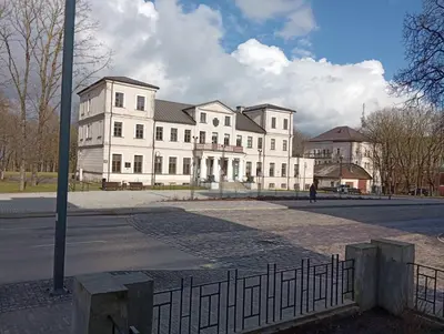 a large white building with a fence in front of it at Old street apartment in Šiauliai