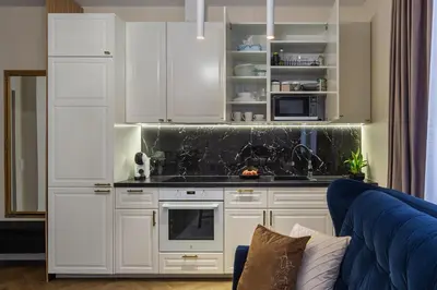 a kitchen with white cabinets and a blue couch at Old street apartment in Šiauliai