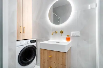 a bathroom with a washing machine and a sink at Paupys Golden Apartment Vilnius in Vilnius