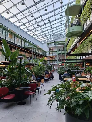 a building with people sitting at tables and plants at Paupys Golden Apartment Vilnius in Vilnius