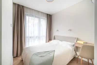 a bedroom with a bed and a desk and a window at Paupys Golden Apartment Vilnius in Vilnius