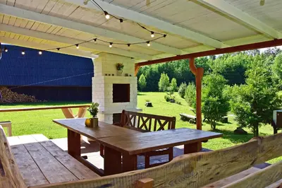 a patio with a wooden table and a fireplace at Pundeliškių sodyba in Šalčininkai
