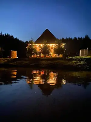 a house with lights in the water at night at Pundeliškių sodyba in Šalčininkai