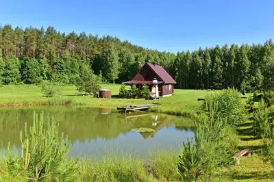 a small cabin next to a pond in a field at Pundeliškių sodyba in Šalčininkai