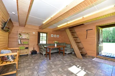 a room with a table and a couch and a staircase at Pundeliškių sodyba in Šalčininkai