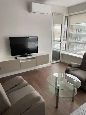 a living room with a tv and a couch and a glass table at Eliana Apartments in Druskininkai