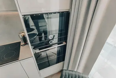 a glass oven in a kitchen next to a curtain at Brand new apartment in Vilnius center. in Vilnius