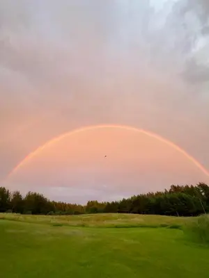 a rainbow in the sky over a golf course at Stripeikių Bitė in Varniškės I