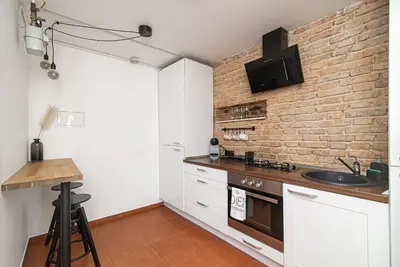 a kitchen with white cabinets and a brick wall at Stylish & Cozy Uzupis Apartment by URBAN RENT in Vilnius