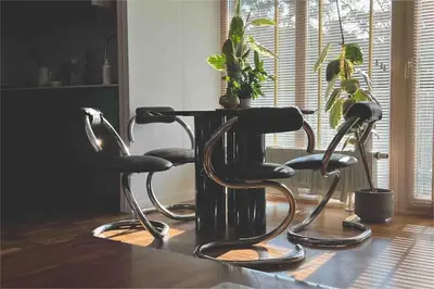 two chairs and a table in a room with a plant at New appartment with art collection in Vilnius