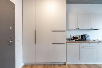 a white kitchen with white cabinets and a counter at #stayhere - Brand New Colourful Studio close to Shopping Malls in Vilnius