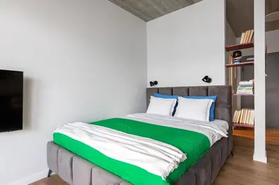 a bedroom with a large bed with green and white sheets at #stayhere - Brand New Colourful Studio close to Shopping Malls in Vilnius