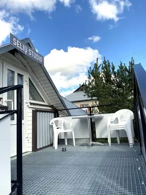 two white chairs sitting on a patio in front of a building at „Sėlių Studio“ Apartamentai in Utena