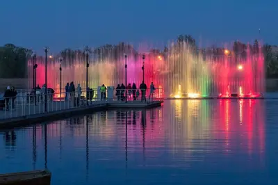 a fountain with colorful lights in the water at night at „Sėlių Studio“ Apartamentai in Utena