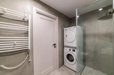 a washer and dryer in a bathroom with a glass door at Frida Elite Apartments in Šiauliai