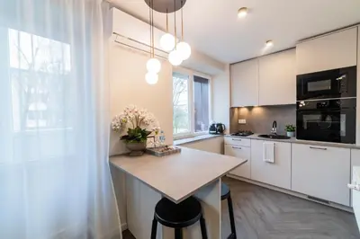 a kitchen with white cabinets and a island with flowers on it at Frida Elite Apartments in Šiauliai