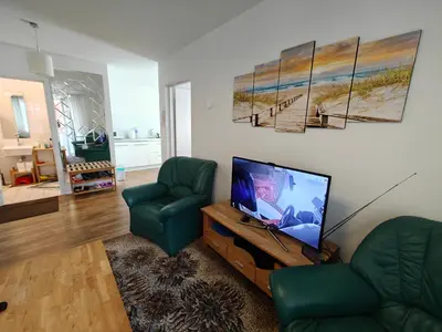 a living room with a flat screen tv and two green chairs at Holiday Ap in Visaginas