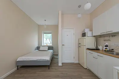 a small kitchen with a bed and a refrigerator at Studio apartment Contrast By Polo Apartments in Kaunas