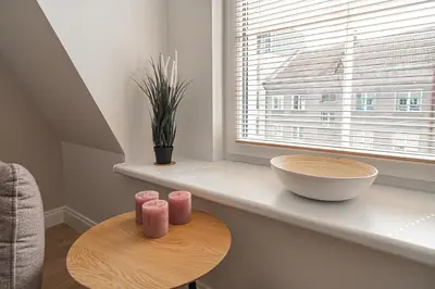 a table with three pink candles on a counter next to a window at G-47 Near the Parliament - Self check in in Vilnius