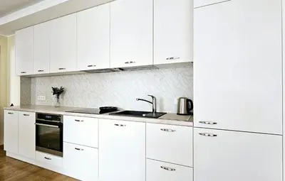 a white kitchen with white cabinets and a sink at Aquapartment Druskininkai in Druskininkai