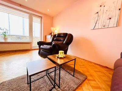 a living room with a leather chair and a coffee table at SPACIOUS Apartment in the SUN CITY in Šiauliai