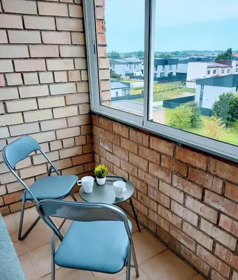 a patio with two chairs and a table and two windows at SPACIOUS Apartment in the SUN CITY in Šiauliai