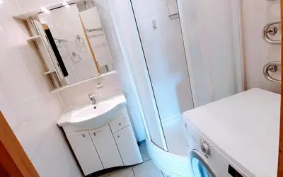 a white bathroom with a sink and a shower at SPACIOUS Apartment in the SUN CITY in Šiauliai